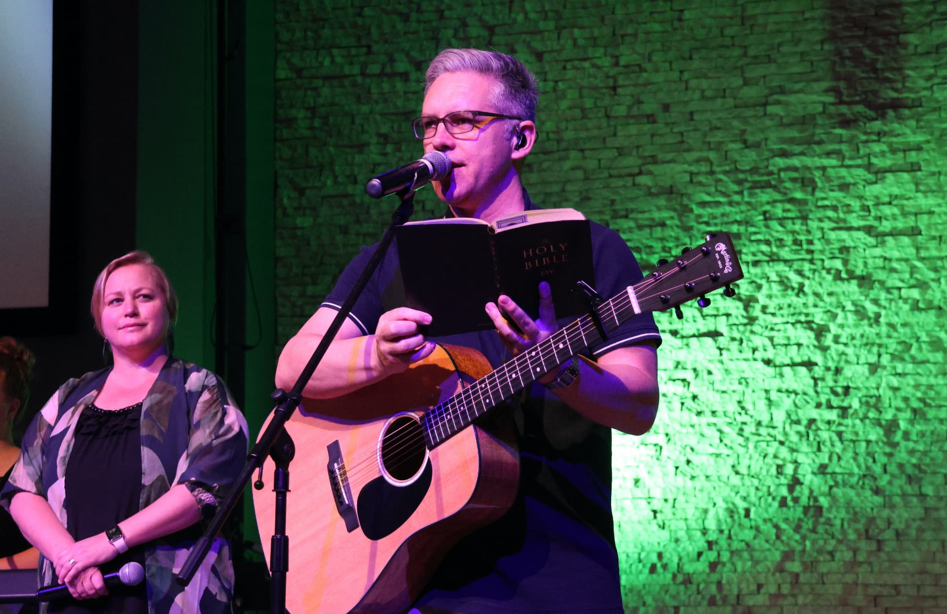 Mark Paul leading worship with a guitar and open Bible